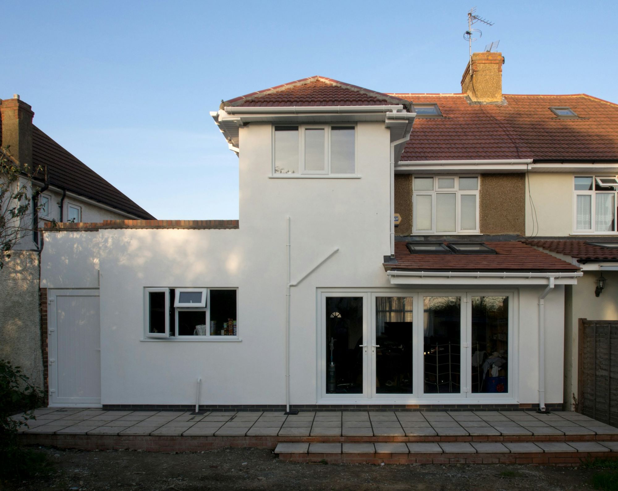 A finished white rear extension with large glass doors onto a garden