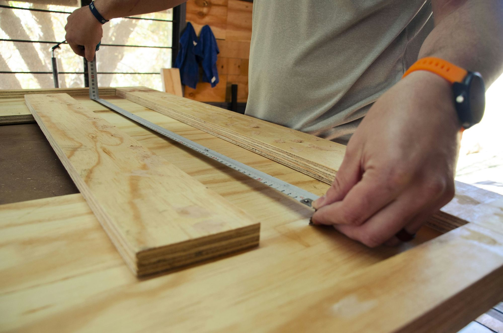 Hands measuring and marking a length of timber on a workbench