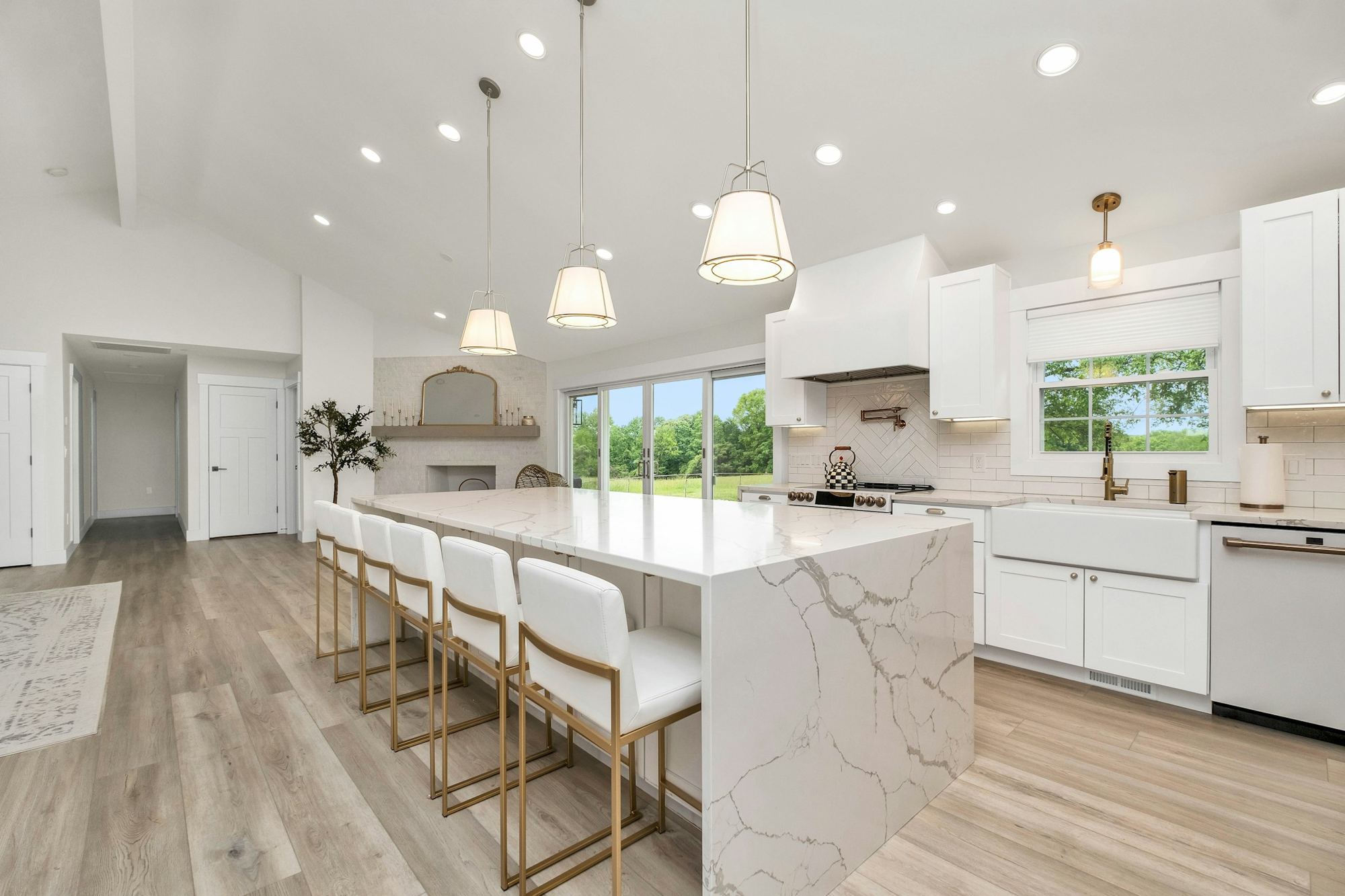 A large fitted kitchen with a marble island and white cabinets