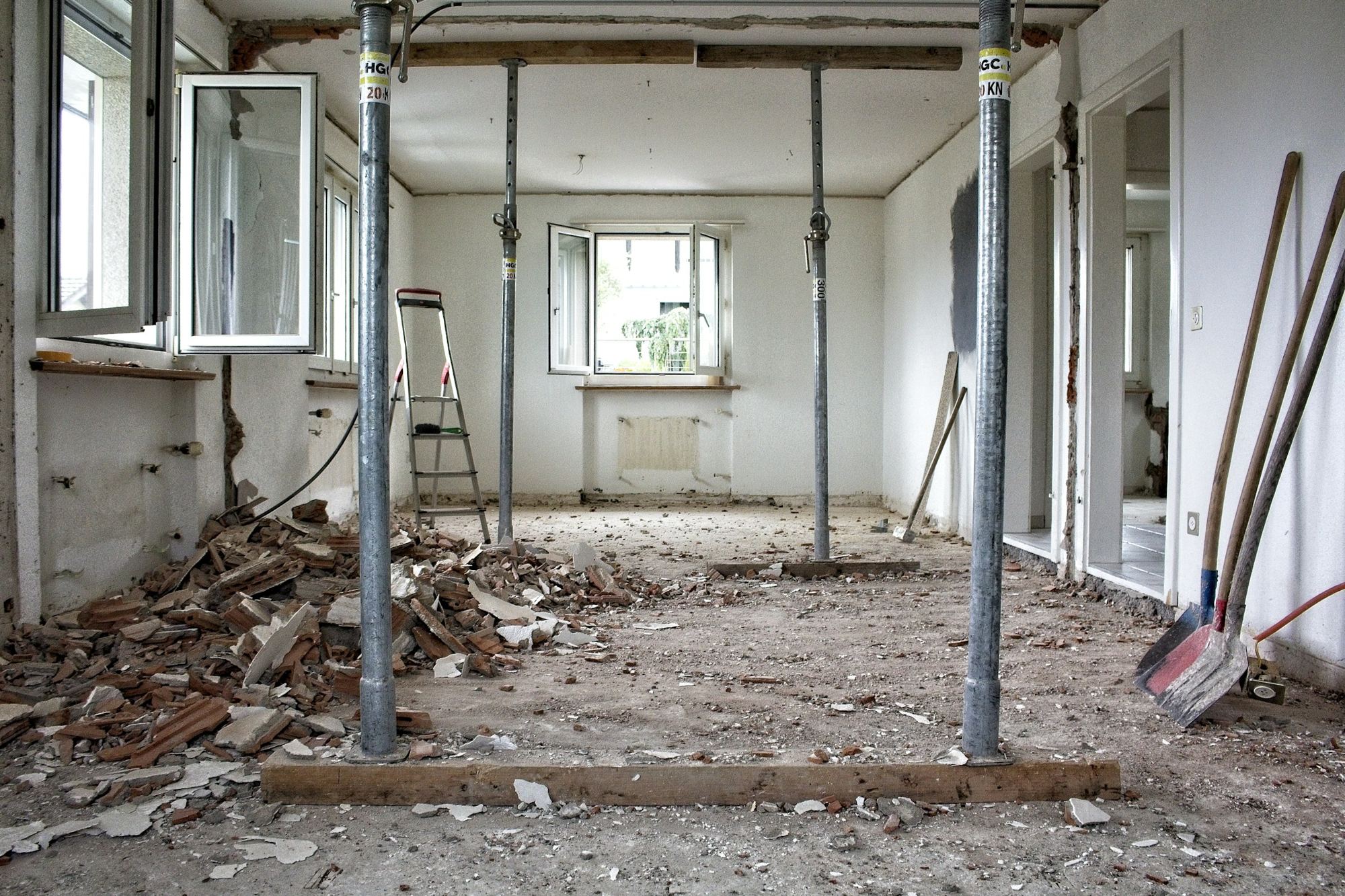 A room stripped back for renovation, with metal props supporting the ceiling