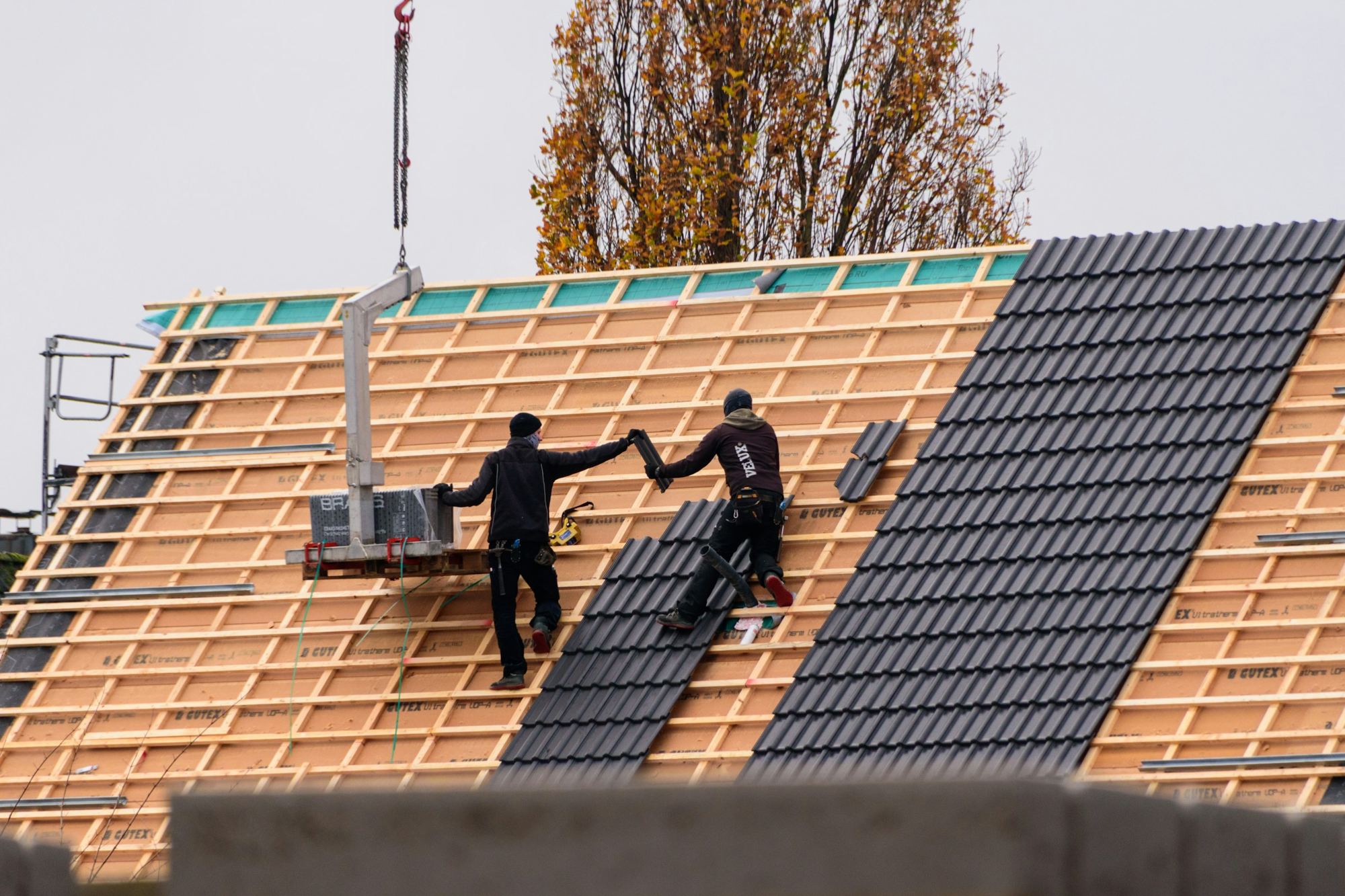 Workers fixing roof tiles on a new building